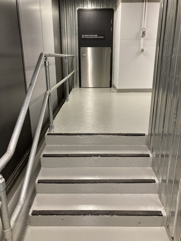 Freshly finished commercial stairwell with anti-slip step nosings and a steel handrail