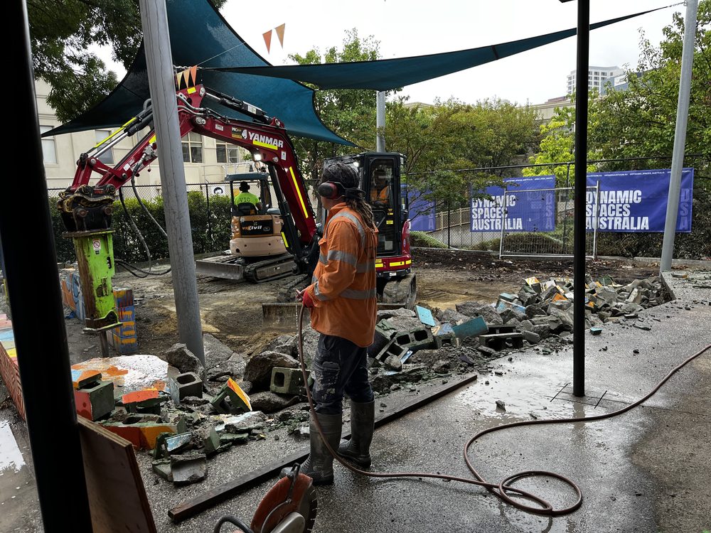 Excavator demolishing a raised planter during a community building upgrade by Dynamic Spaces Australia