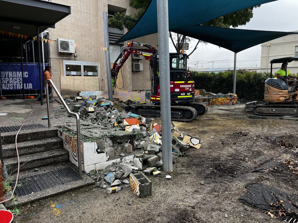 Excavation works beside a commercial building with orange safety fencing and DSA signage