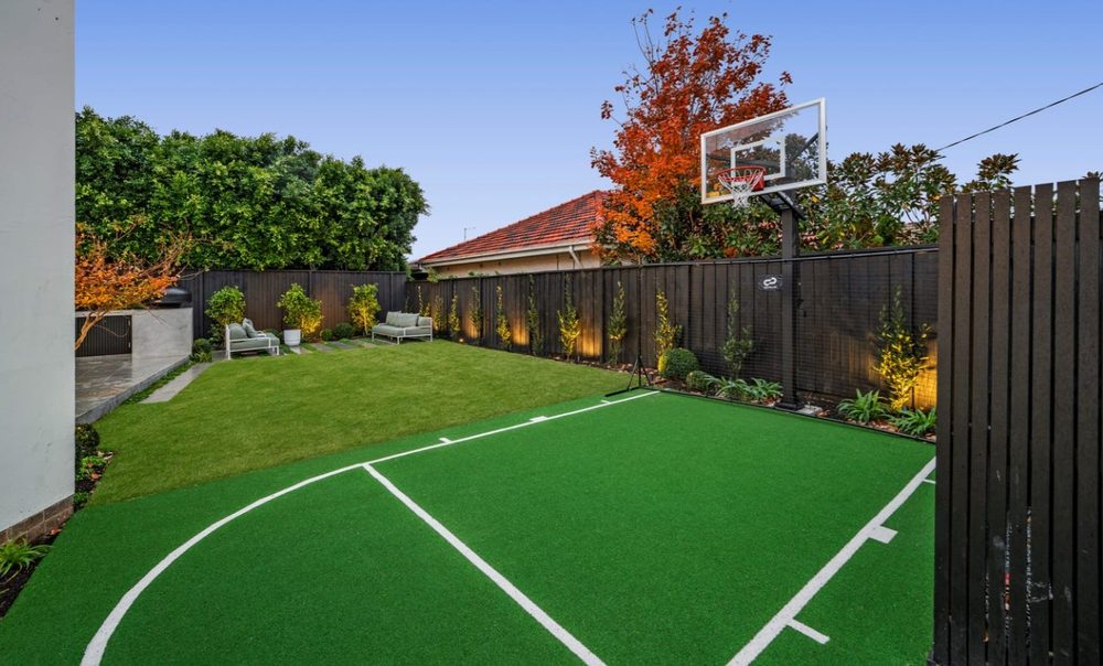 Backyard with a synthetic-turf basketball half-court, lawn and lounge area