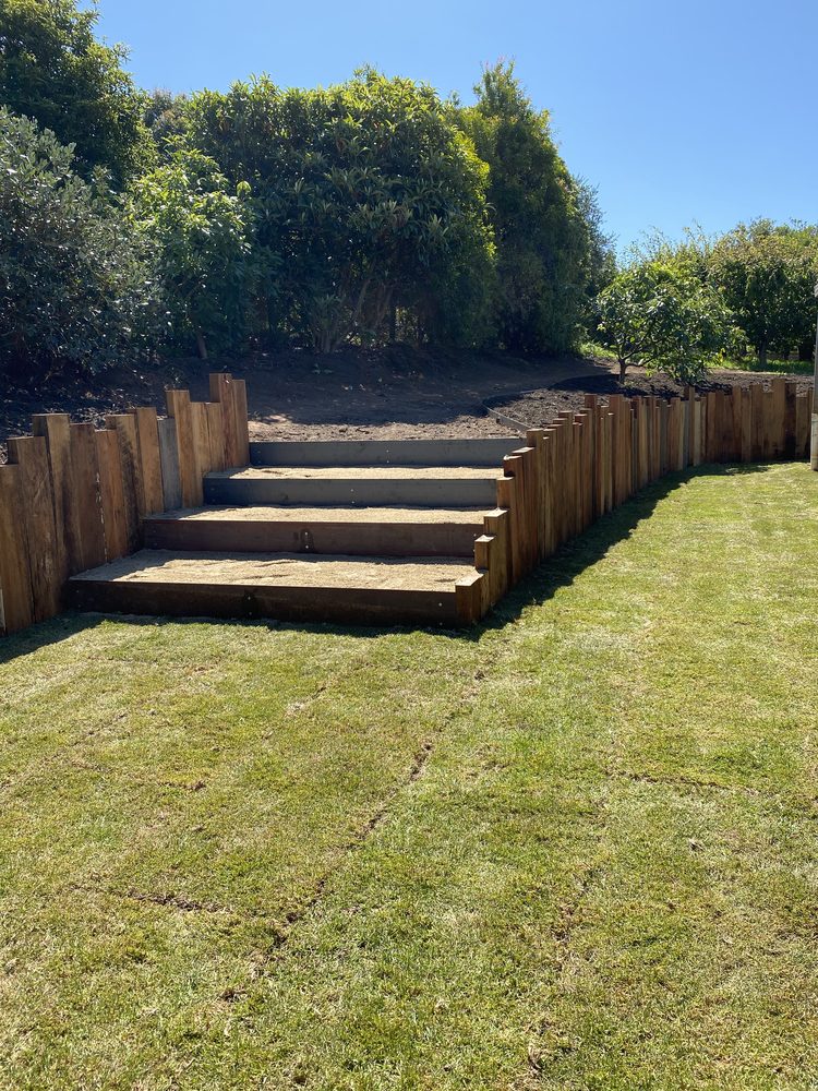 Timber sleeper retaining wall and steps with newly laid turf on a sloping garden