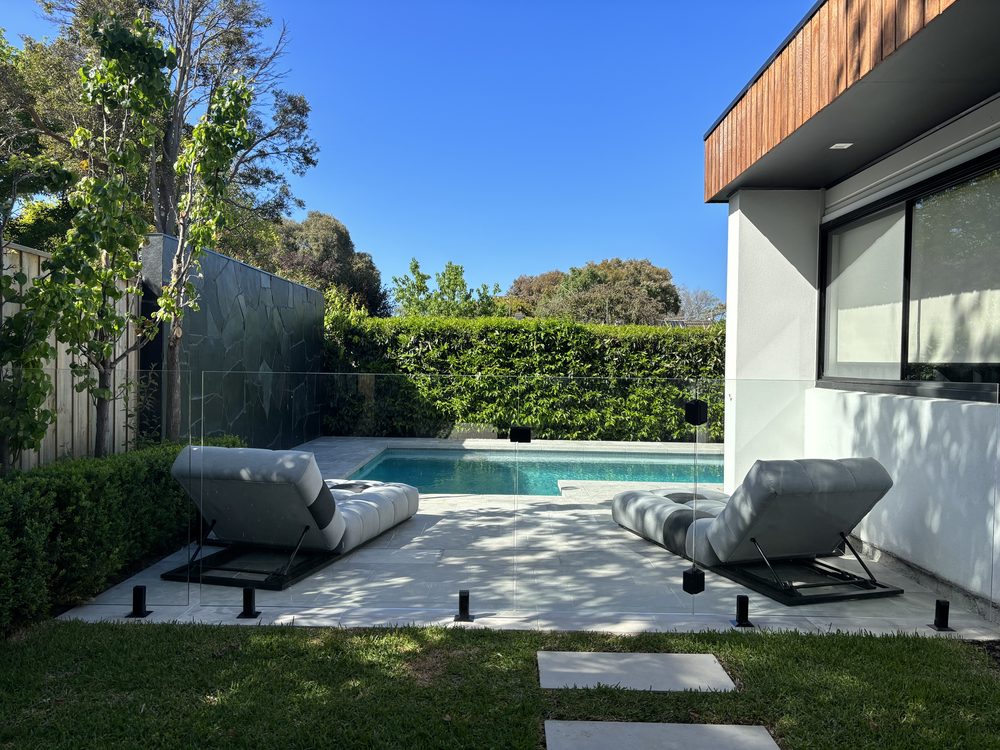 Frameless glass pool fence on a raised timber pool deck on a sloping block