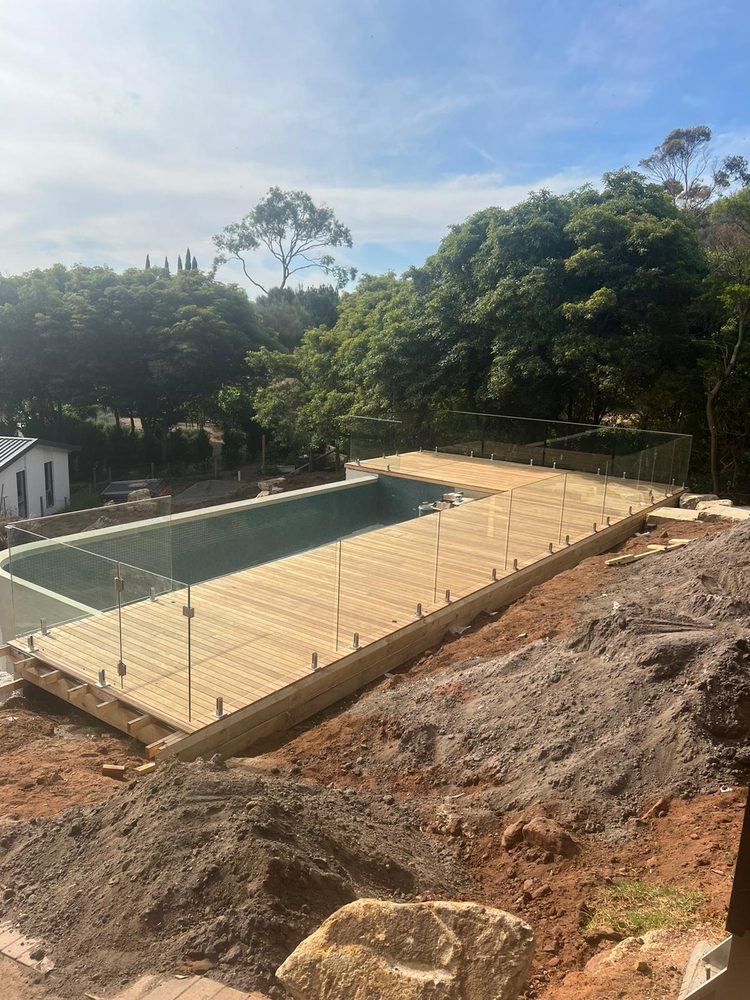 Frameless glass pool fence between a pool and lawn in a family backyard