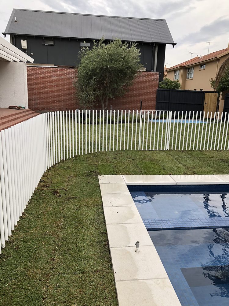 White aluminium batten pool safety fence enclosing a pool and lawn