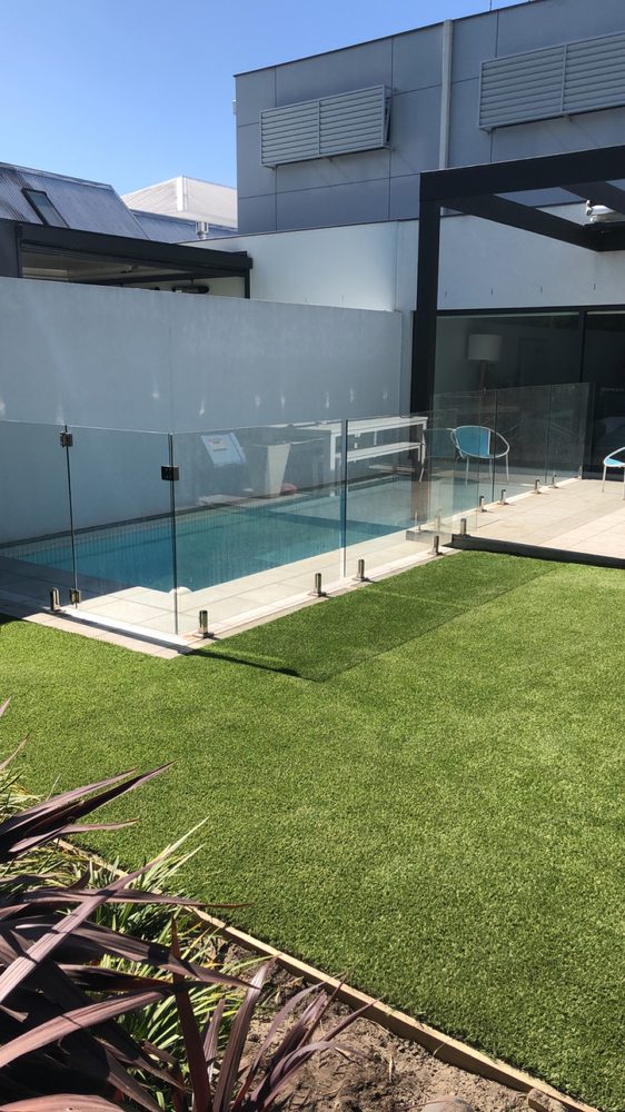 Frameless glass pool fence beside a blue-tiled pool and covered alfresco